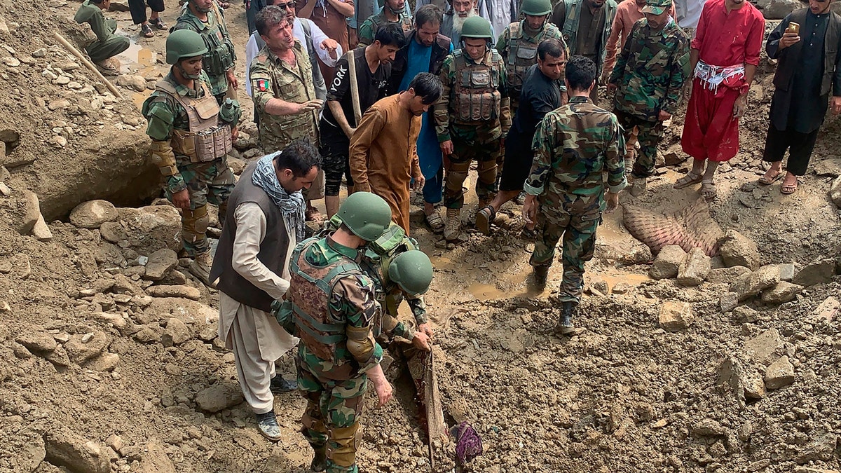 Soldiers and locals search for victims in a mudslide following heavy flooding in the Parwan province, north of Kabul, Afghanistan, Wednesday, Aug. 26, 2020.
