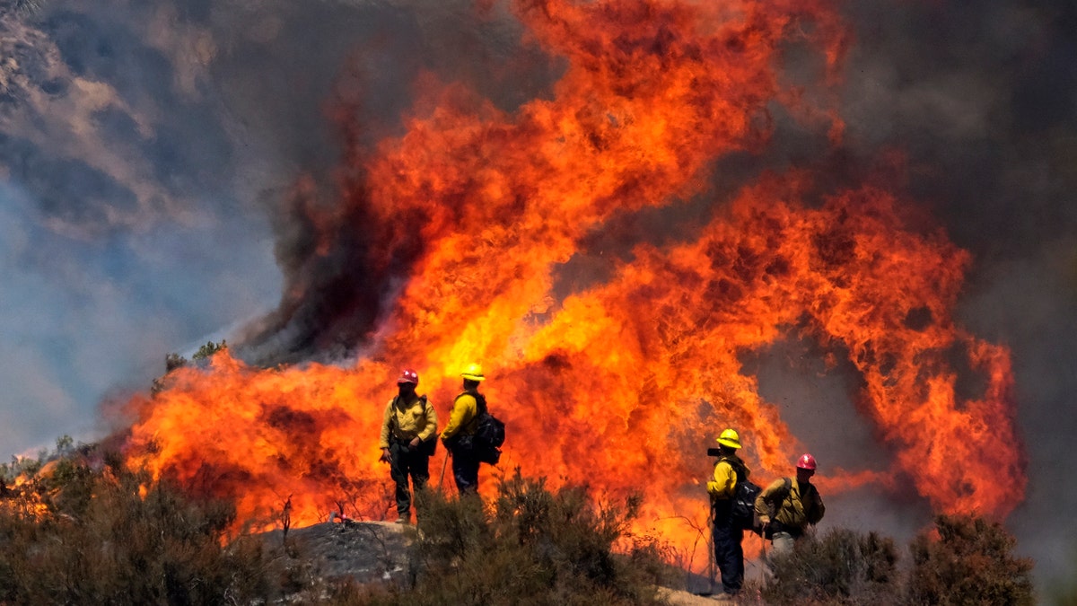 Firefighters watch the Apple Fire in Banning, Calif., Sunday, Aug. 2, 2020.