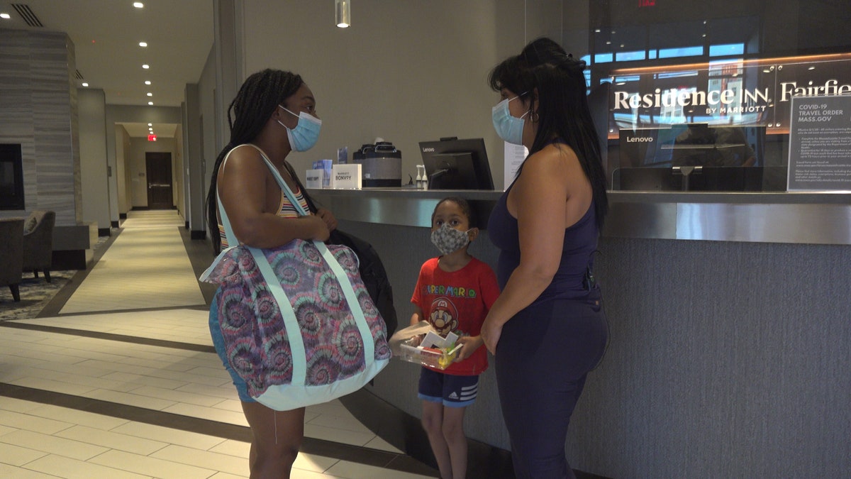 Gladys Vega, executive director of the Chelsea Collaborative, hands over a hotel key to Elizabeth Souffrant so she and her son don't have to sleep in her car.