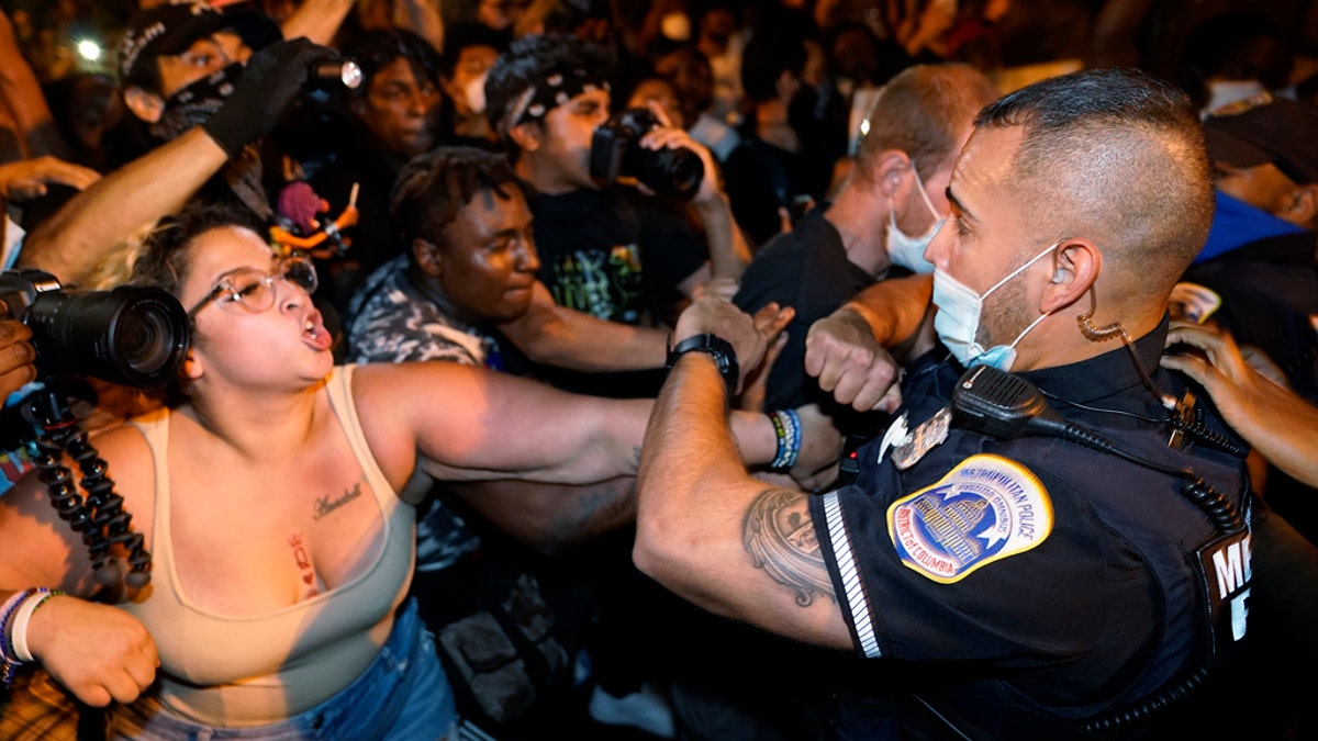 Metropolitan Police are confronted by protesters as police carry away a handcuffed protester along a section of 16th Street Northwest, renamed Black Lives Matter Plaza, Aug. 27, 2020, in Washington. (AP Photo/Julio Cortez)