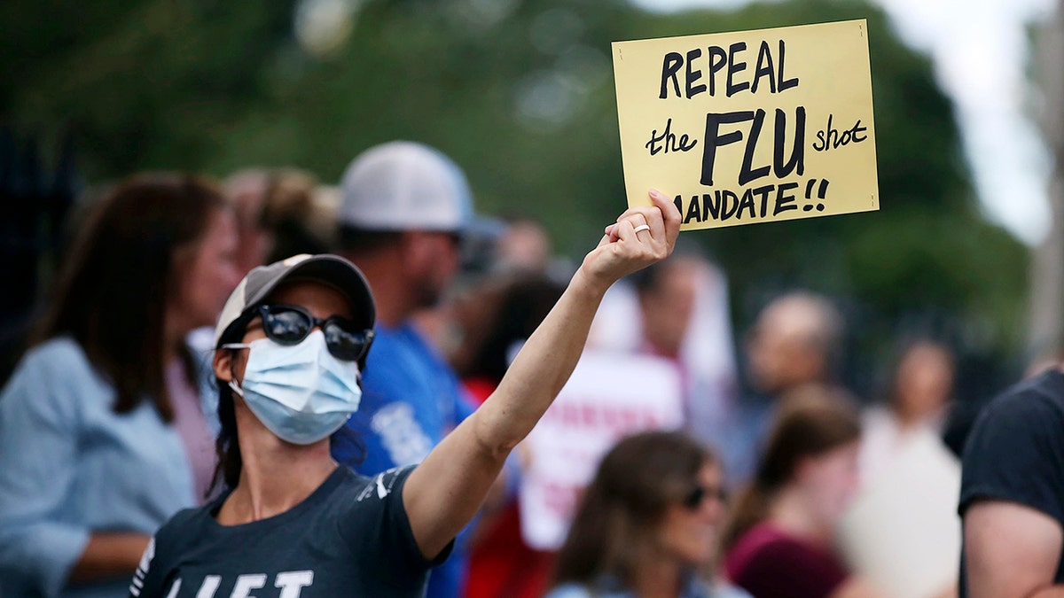 Teresa Hays, of Clinton, holds a sign during a protest against mandatory flu vaccinations, outside the Massachusetts State House, Sunday, Aug. 30, 2020, in Boston. Public health authorities say flu shots are very important this year to avoid overburdening the health system. amid the coronavirus pandemic. (Nancy Lane/Boston Herald via AP)