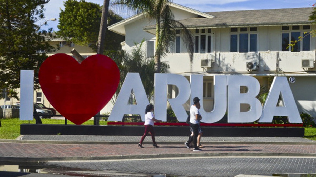 tourists walking around i love aruba sign