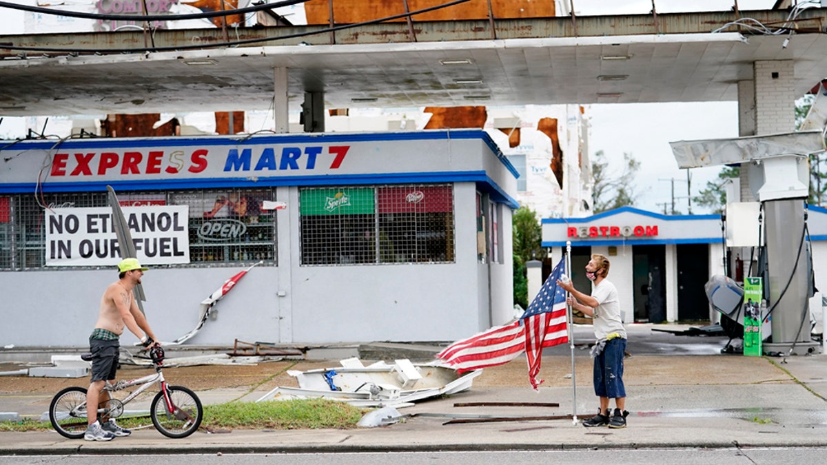 Dustin Amos, right, walks near debris at a gas station on Thursday, Aug. 27, 2020, in Lake Charles, La., after Hurricane Laura moved through the state.