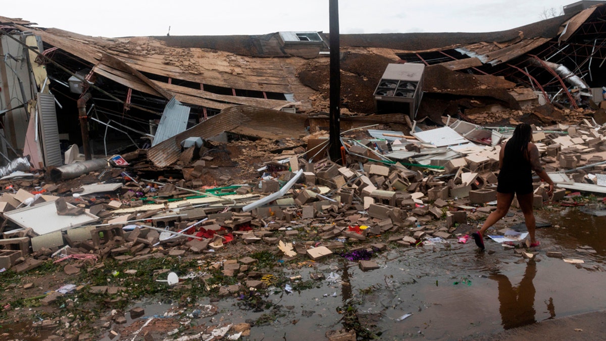 People walk past a destroyed building after the passing of Hurricane Laura in Lake Charles, Louisiana on August 27, 2020.