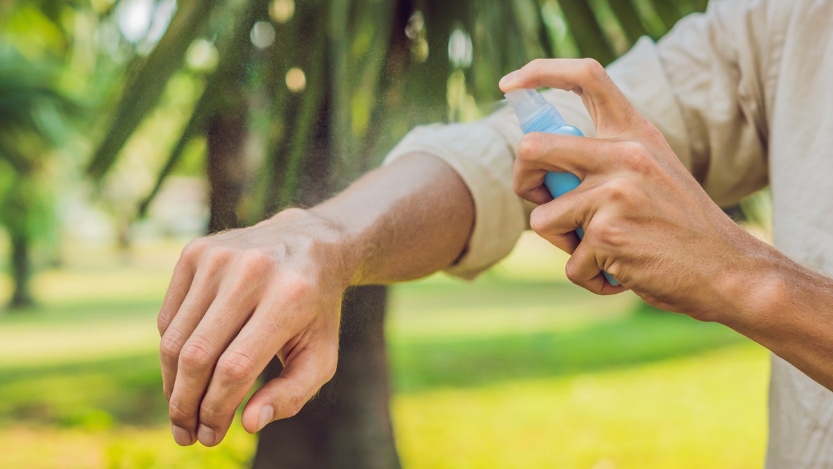 spraying mosquito repellant