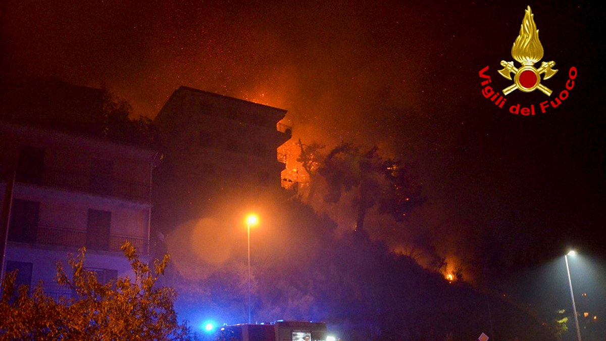Flames burn behind buildings in the town of Altofonte, near the Sicilian city of Palermo, southern Italy, Saturday, Aug. 29, 2020.