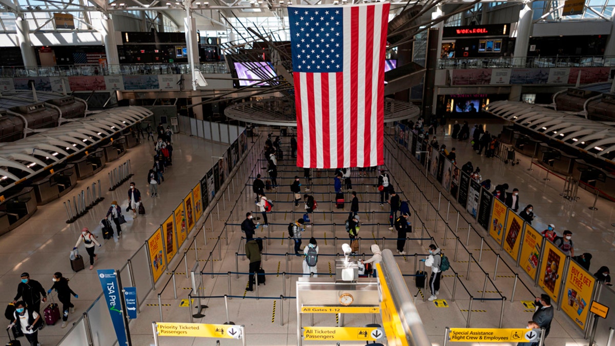 Passengers, some wearing masks and protective gear, queue for their flight at Terminal 1 of John F. Kennedy Airport. (Getty Images)