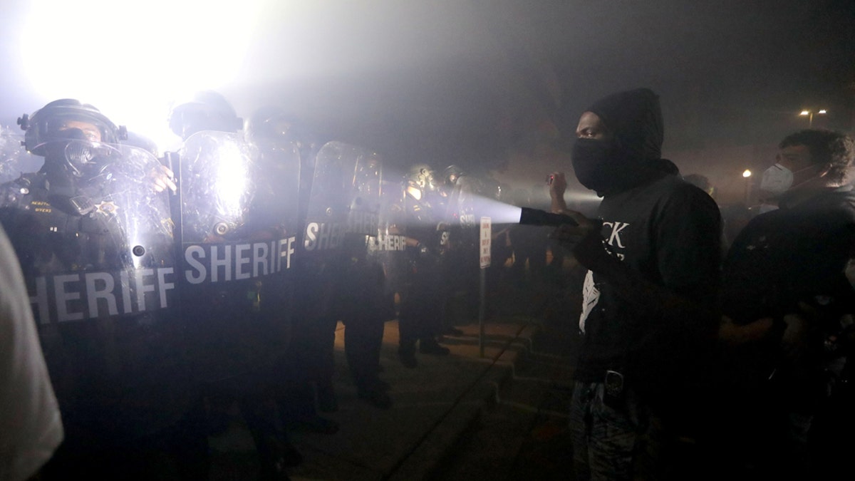 A protestor shines a flashlight in the direction of Kenosha County Sheriffs Deputies outside the Kenosha Police Department in Kenosha, Wisconsin, U.S., during protests following the police shooting of Black man Jacob Blake August 23, 2020. Mike De Sisti/Milwaukee Journal Sentinel via USA TODAY via REUTERS MANDATORY CREDIT - RC2DKI917GNT