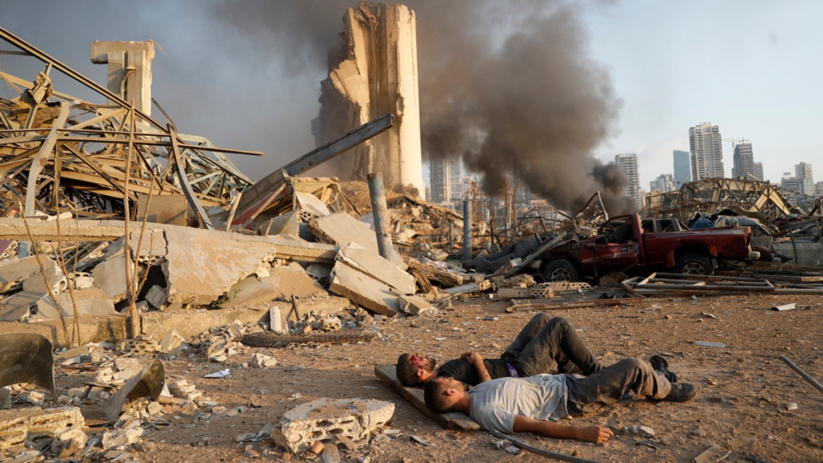 Two injured men lie on the ground, waiting for help at the explosion scene that hit the seaport, in Beirut Lebanon, Tuesday, Aug. 4, 2020. (AP Photo/Hussein Malla)