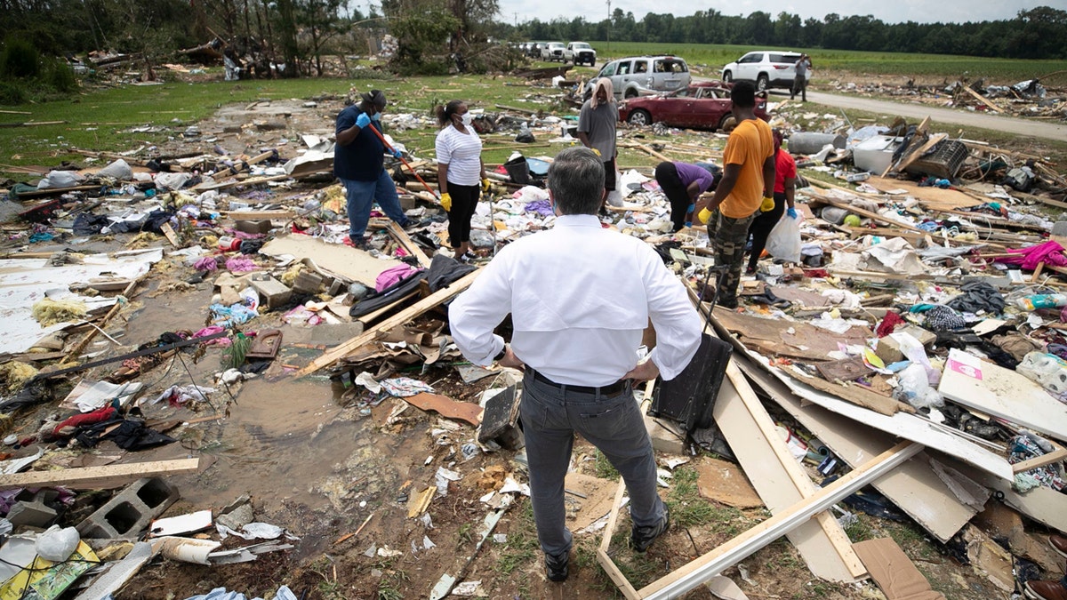 North Carolina Gov. Roy Cooper talks with residents, Wednesday, Aug. 5, 2020, as they looks for personal items in the rubble after a tornado spawned by Hurricane Isaias destroyed a rural mobile home neighborhood killing two residents near Windsor N.C.