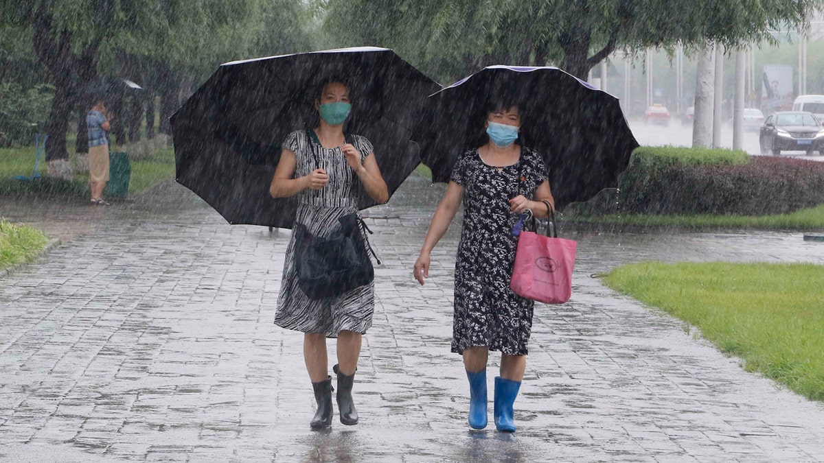 Women walk with umbrellas during torrential rains, Wednesday, August 5, 2020, in Pyongyang.