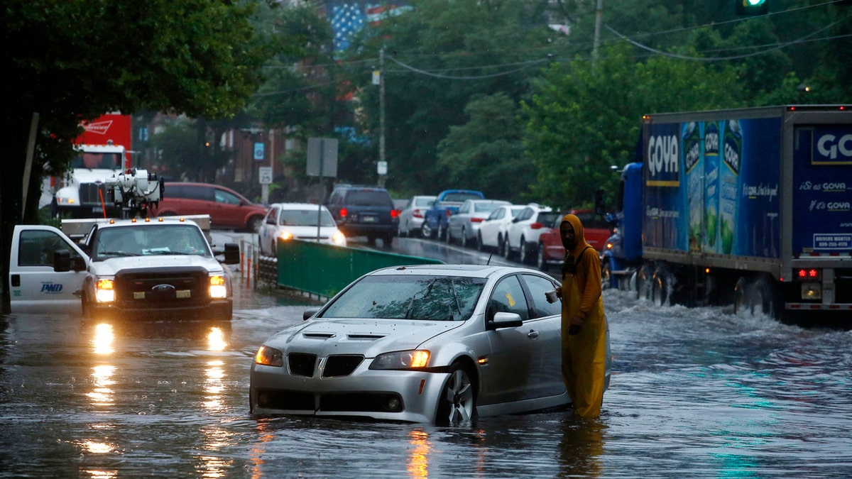 A man checks on a stranded vehicle during Tropical Storm Isaias, Tuesday, Aug. 4, 2020, in Philadelphia. The storm spawned tornadoes and dumped rain during an inland march up the U.S. East Coast after making landfall as a hurricane along the North Carolina coast. (AP Photo/Matt Slocum)