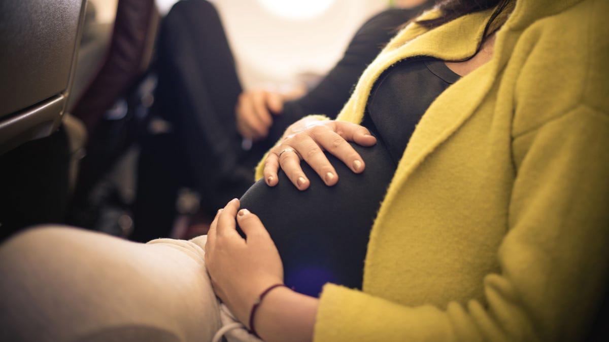 Pregnant woman traveling with airplane. Close up.