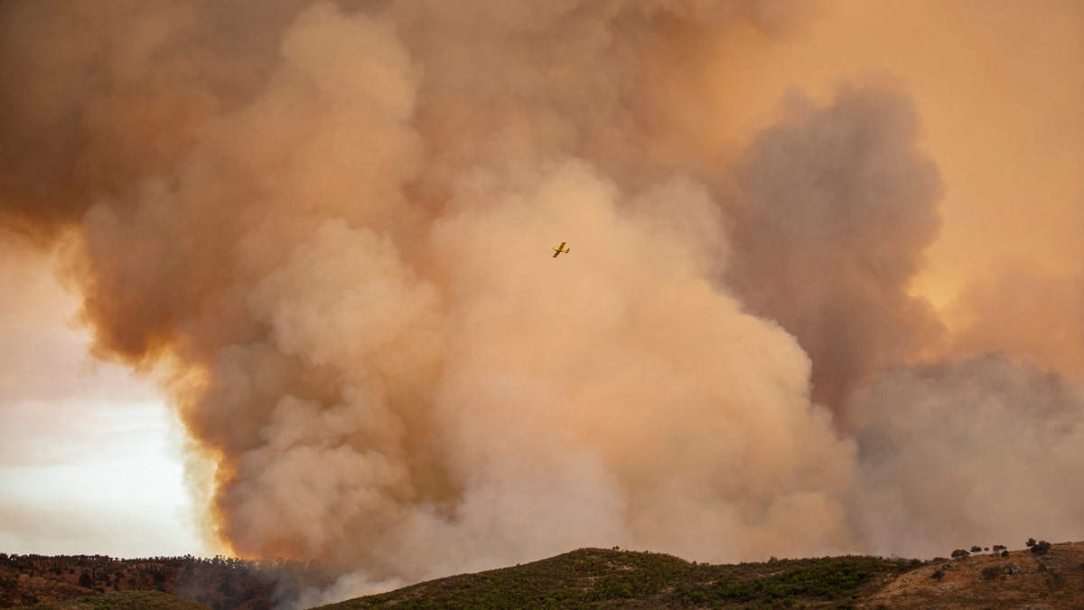 A hydroplane flies over a wildfire in Almonaster la Real in Huelva, Spain, Thursday Aug. 27, 2020.