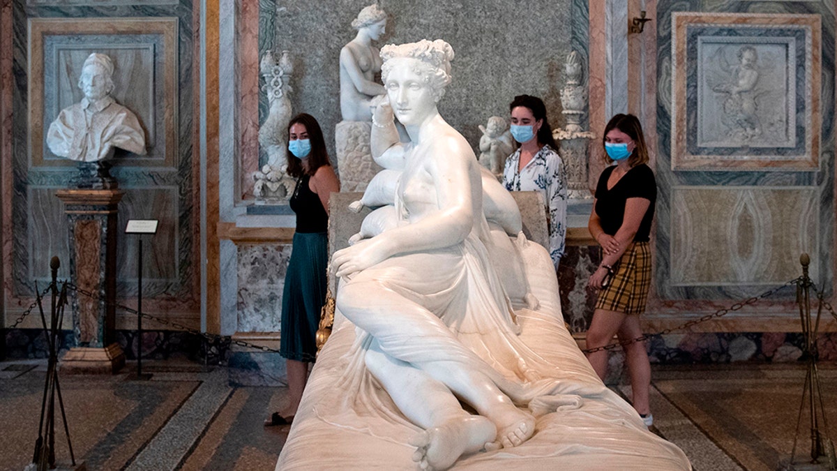Visitors wearing a face mask view "Paolina Borghese Bonaparte as Venus Victrix", an 1805-1808 marble sculpture by Antonio Canova at the Galleria Borghese museum in Rome on May 19, 2020. (Photo by Tiziana FABI / AFP) (Photo by TIZIANA FABI/AFP via Getty Images)