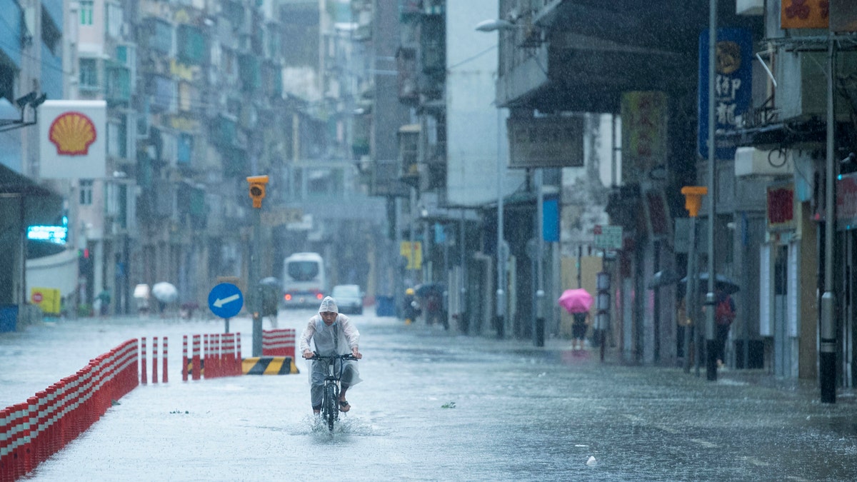 In this photo released by China's Xinhua News Agency, a man rides a bicycle during a rainstorm in Macao, Wednesday, Aug. 19, 2020.