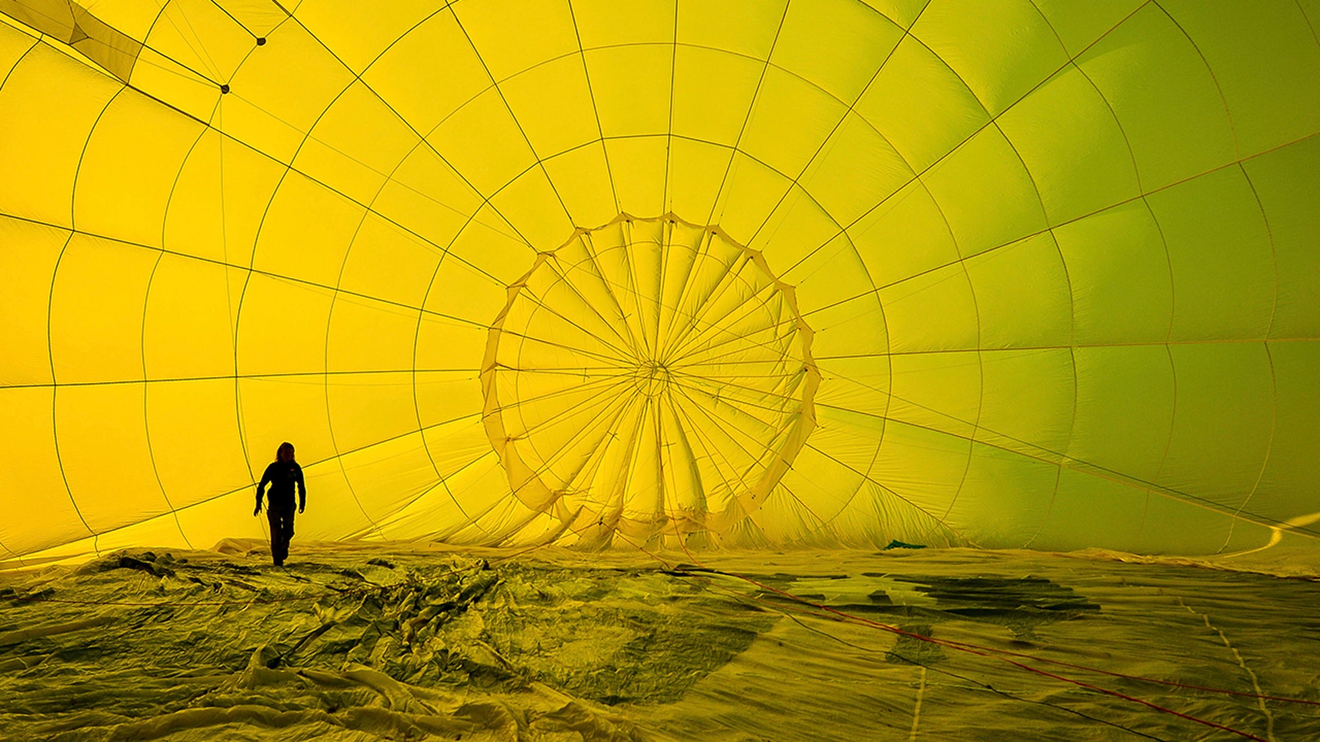 A hot air balloon pilot checks her rigging inside the canopy before a mass ascent with 43 balloon teams taking part in the Fiesta Flypast over the city of Bristol, England, Aug. 3, 2020. 