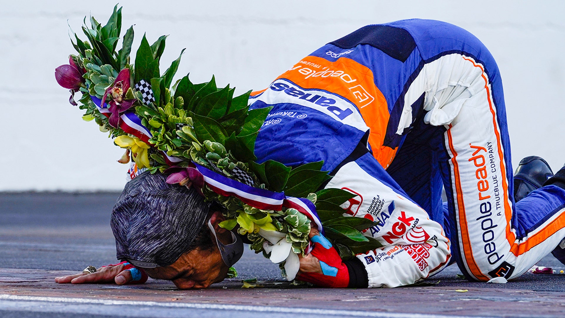 Takuma Sato, of Japan, kisses the yard of bricks on the start/finish line after winning the Indianapolis 500 in Indianapolis, Aug. 23, 2020. 