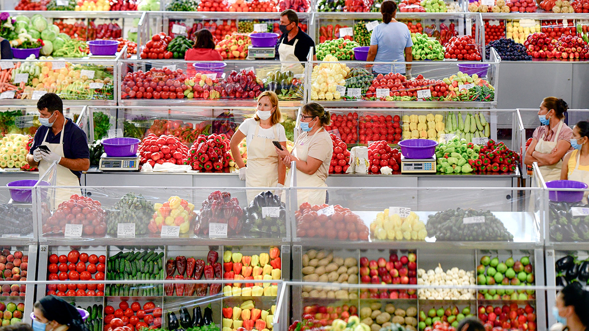 Fruit and vegetable vendors, wearing masks against the spread of the COVID-19 infections, wait for customers at a market in Bucharest, Romania, Aug. 11, 2020.
