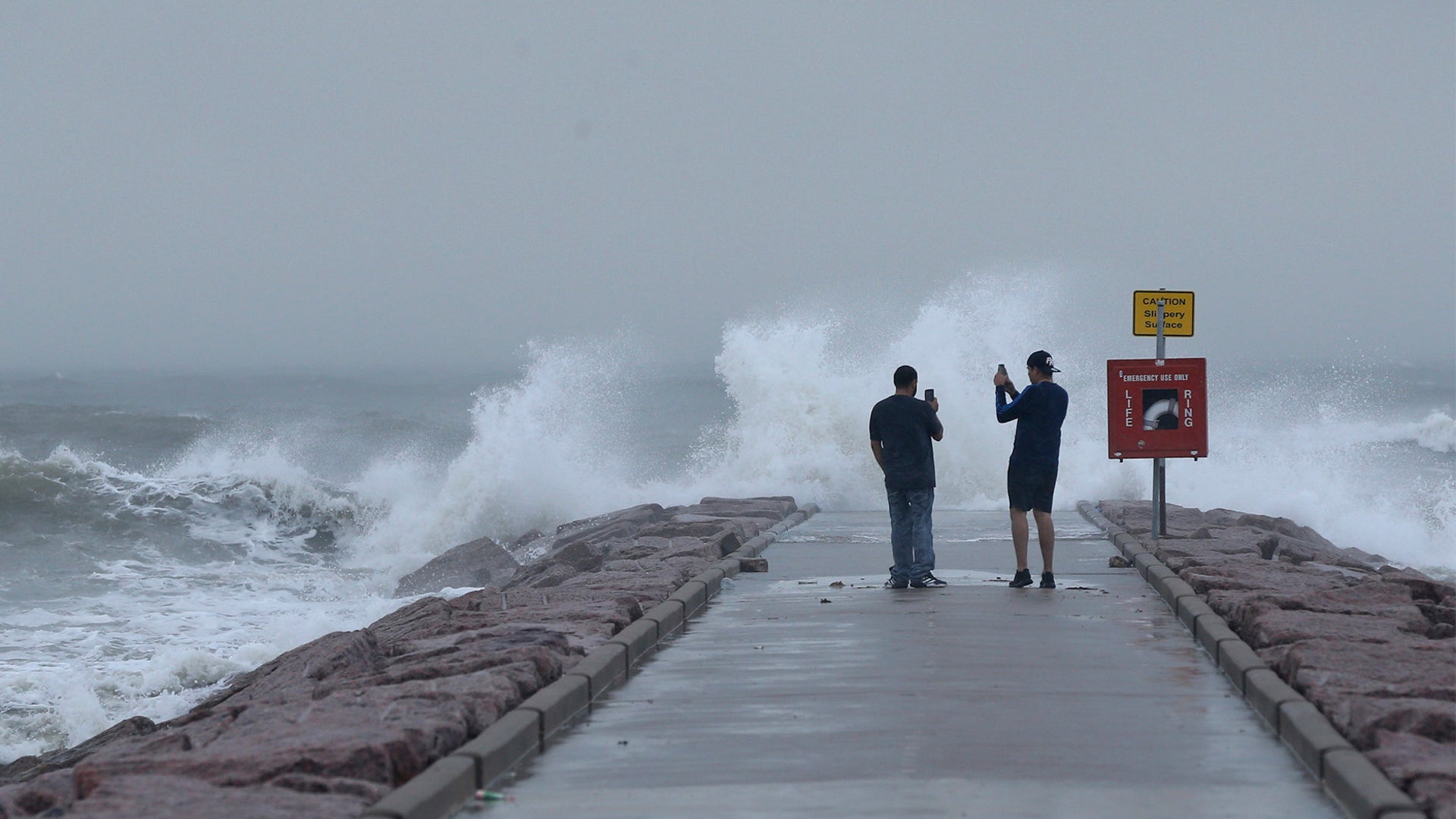 Josue Blanco, left, and Alex Mendez photograph waves generated by Hurricane Laura as they crash into the rock groin at 37th Street in Galveston, Texas on Aug. 26.