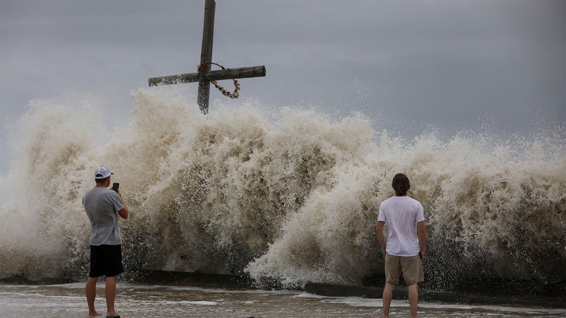 Mark Allums, left, and Hunter Clark watch waves crash ashore as outer bands from Hurricane Laura begin to hit the coast Aug. 26, in High Island.
