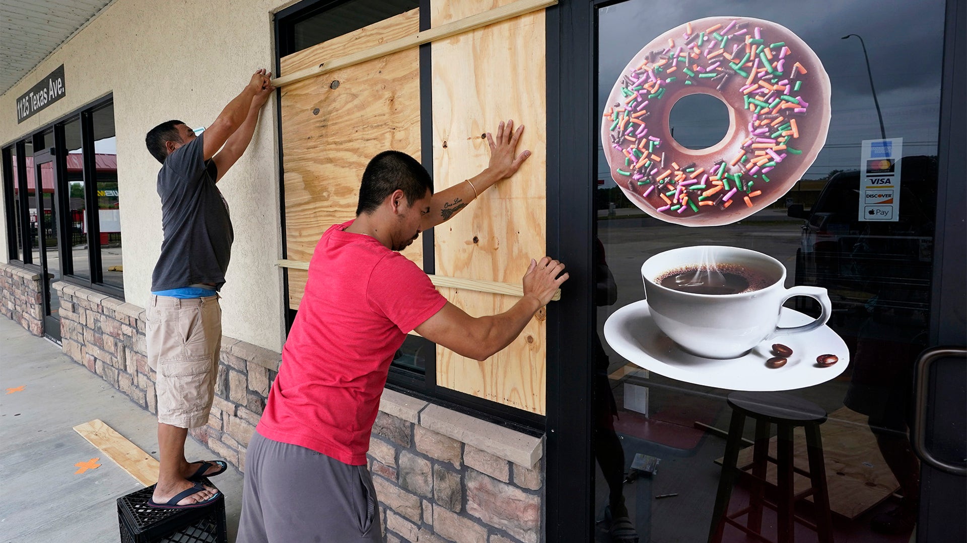 Daoith Porm, right, and Bunsant Khov, left, board their business with Hurricane Laura just hours away, Aug. 26, in Bridge City, Texas.