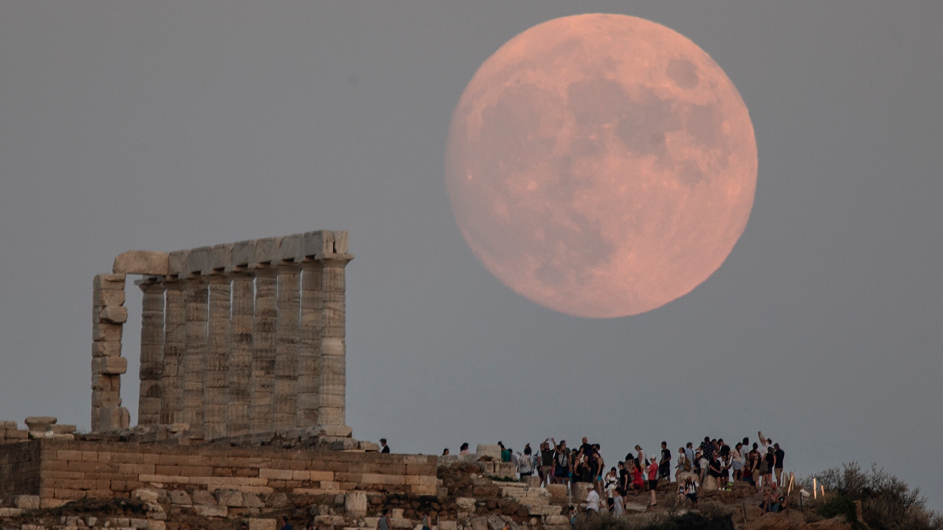 The moon rises behind the columns of the ancient marble Temple of Poseidon at Cape Sounion, Greece, Aug. 2, 2020. 