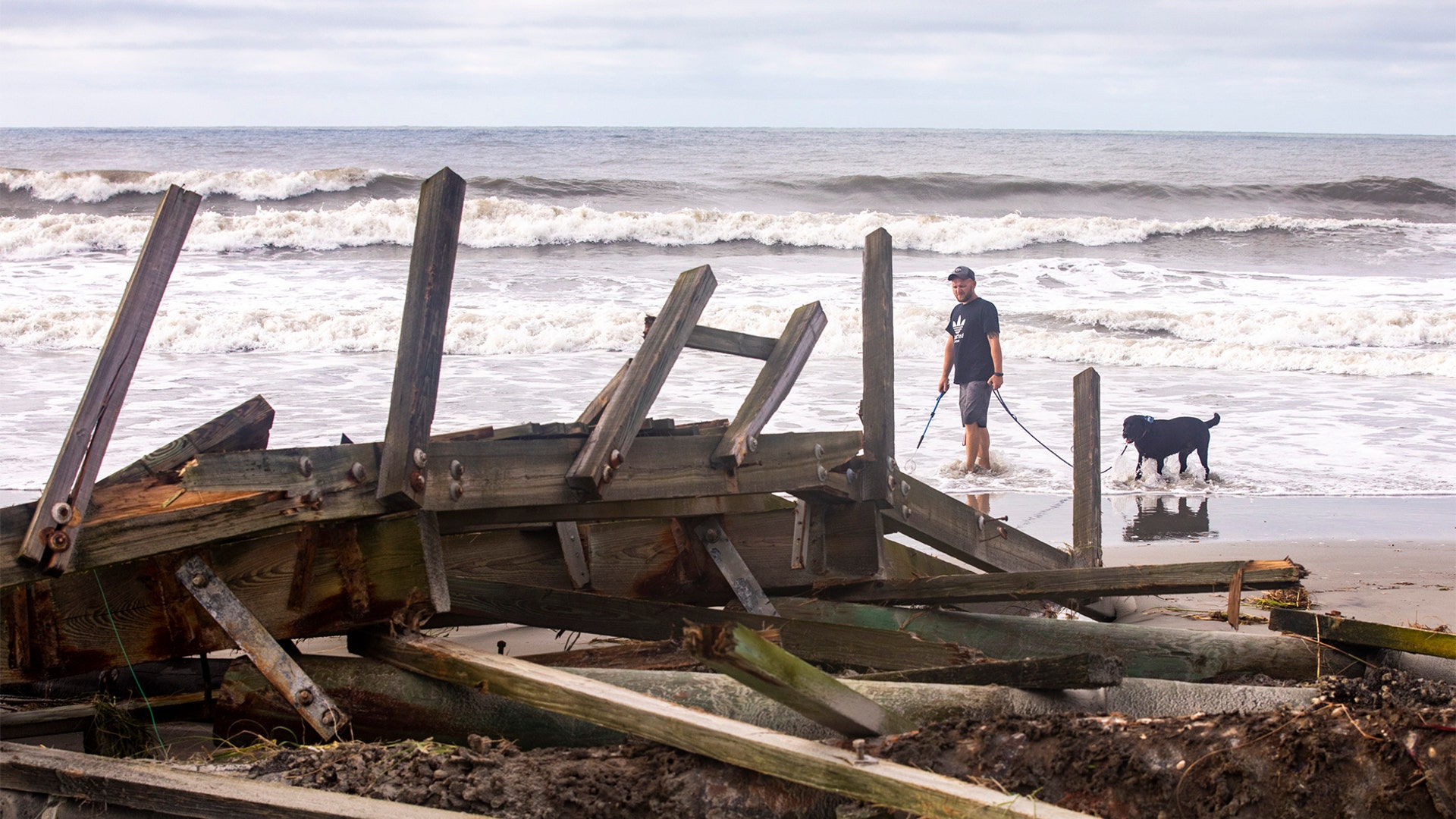 A passerby looks at docks damaged by a storm surge from Hurricane Isaias on North Myrtle Beach in S.C., Tuesday, Aug. 4, 2020.