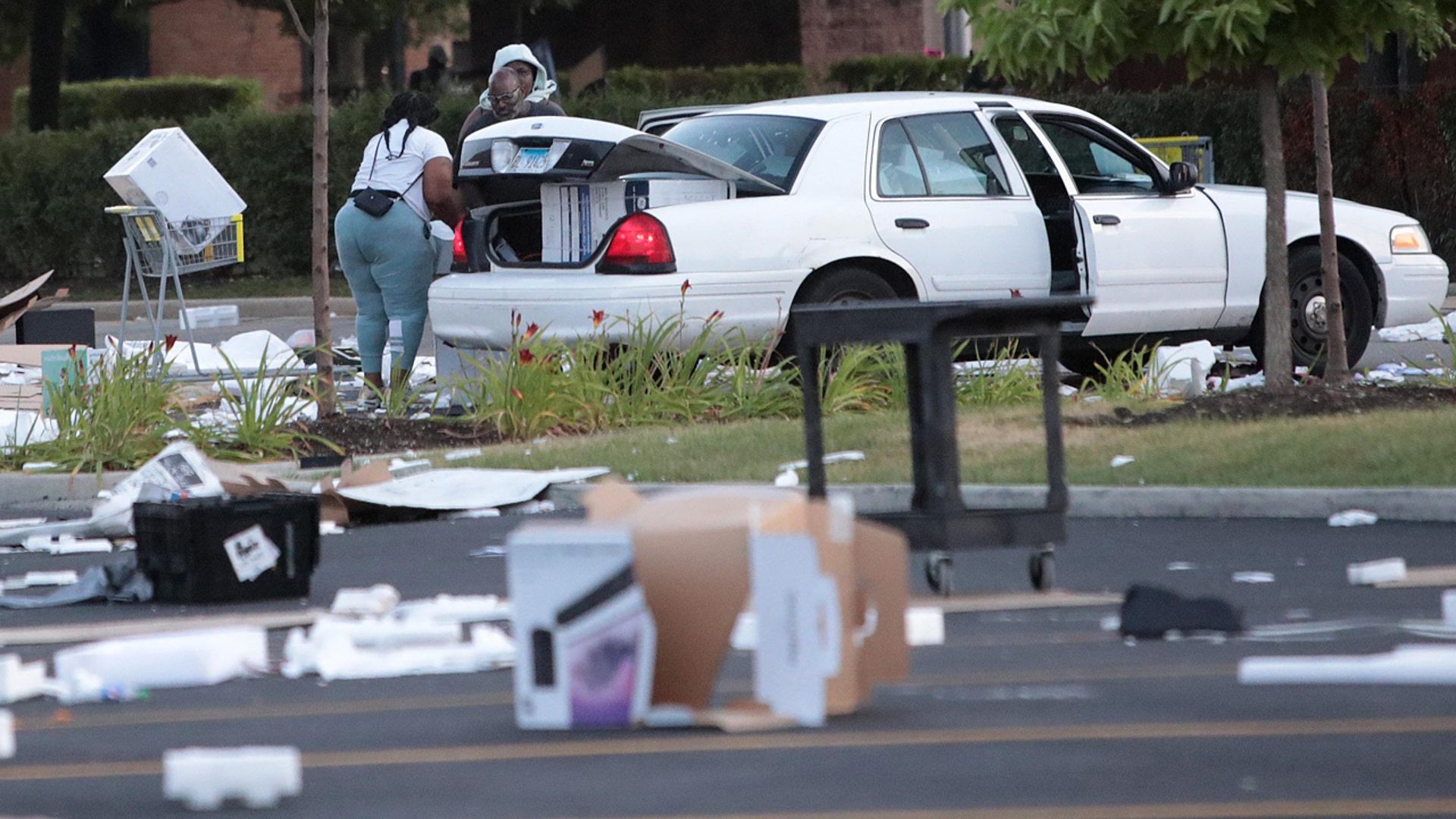 People load merchandise into a car near a looted Best Buy store after parts of the city had widespread looting and vandalism, on Aug. 10, 2020 in Chicago, Ill.