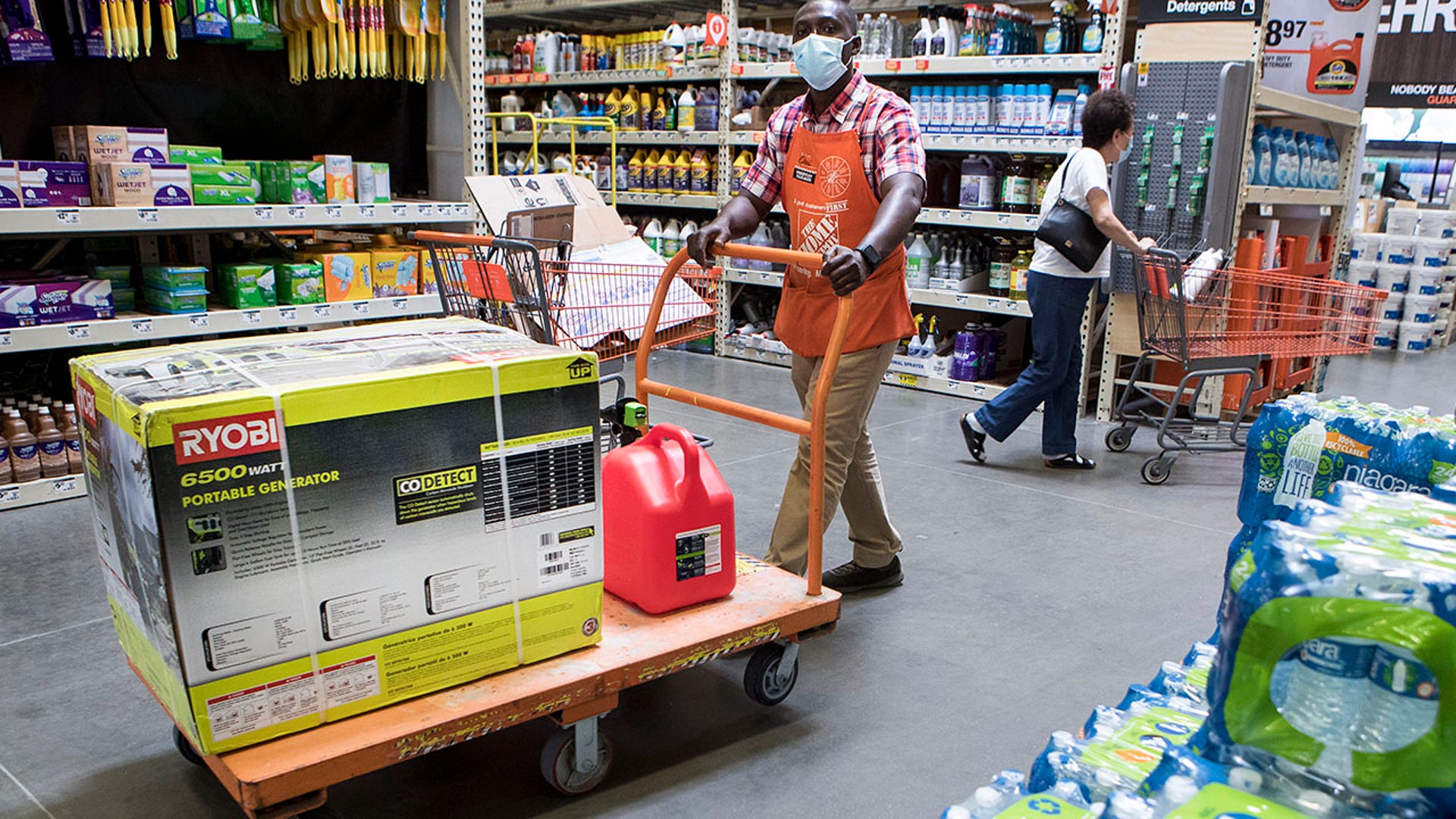 man, assistant operations manager, wheels a portable generator to the checkout stand for a customer at a Home Depot store as residents prepare for the possible landfall of Hurricane Laura on Tuesday, Aug. 25, 2020 in Houston. (Brett Coomer/Houston Chronicle via AP)
