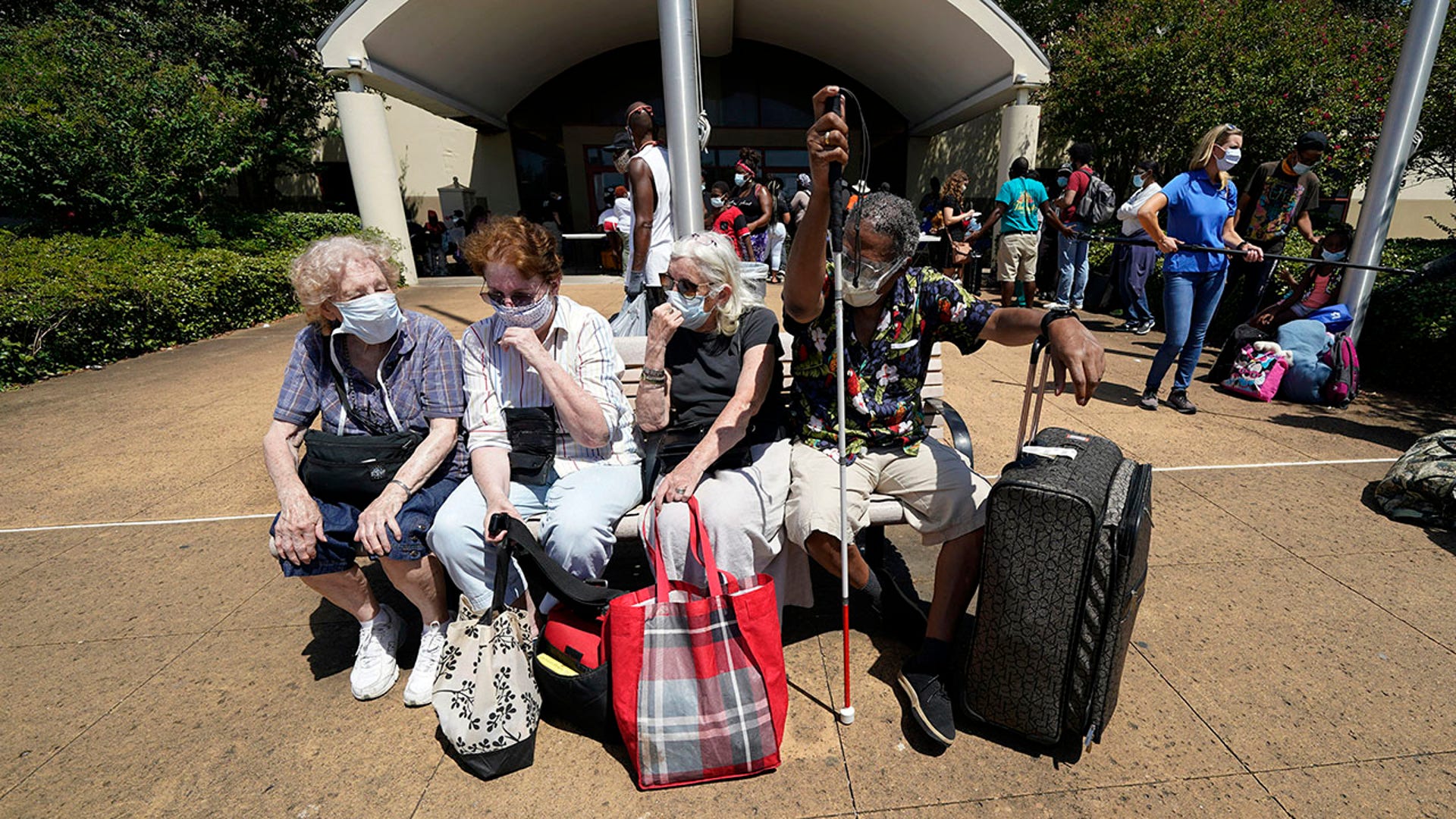 CORRECTS SPELLING OF FIRST NAME TO ELISABETH INSTEAD OF ELIZABETH - Evacuees, from right to left, Tommie McNeil, Elisabeth Pelham, Nota Norris, and a woman who did not want to be identified, wait to board a bus as they evacuate, Tuesday, Aug. 25, 2020, in Galveston, Texas. The evacuees are being taken to Austin, Texas, as Hurricane Laura heads toward the Gulf Coast. (AP Photo/David J. Phillip)