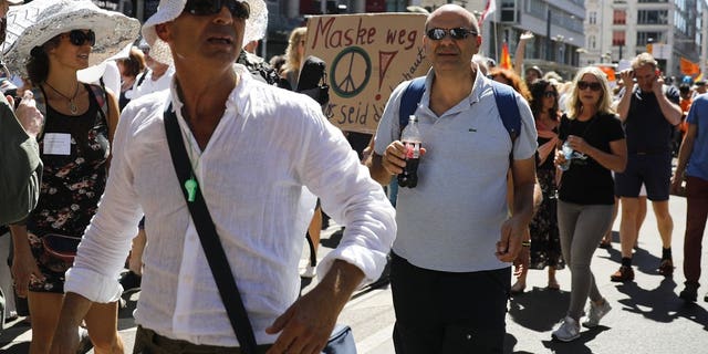 Protestors show a poster reading: 'Mask away' as they attend a demonstration with the slogan ‚The end of the pandemic - freedom day' - against coronavirus restrictions in Berlin, Germany, Saturday, Aug. 1, 2020. It comes amid increasing concern about an upturn in infections in Germany.