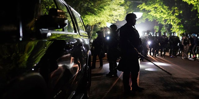 Portland police officers walk through the Laurelhurst neighborhood after dispersing protesters from the Multnomah County Sheriff's Office early in the morning on Saturday, Aug. 8, 2020 in Portland, Ore. (Associated Press)