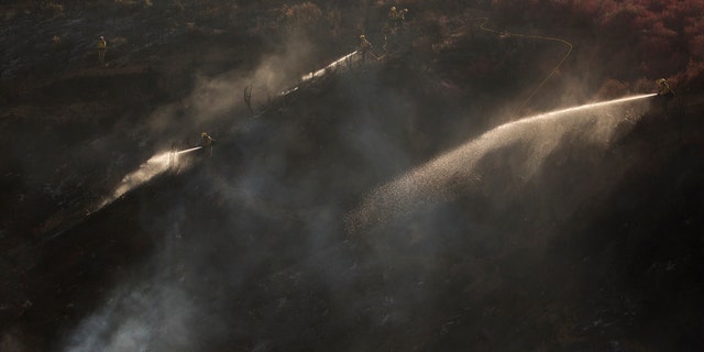 Hand crews work on the remaining hot spots from a brush fire at the Apple Fire in Cherry Valley, Calif., Saturday, Aug. 1, 2020.