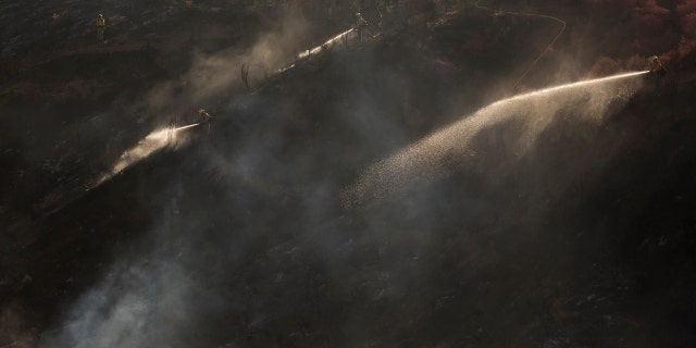 Hand crews work on the remaining hot spots from a brush fire at the Apple Fire in Cherry Valley, Calif., Saturday, Aug. 1, 2020.