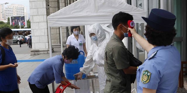 People disinfect their hands and take their temperatures before going to Pyongyang Railway Station in Pyongyang, North Korea, on Thursday, August 13, 2020. (AP Photo / Cha Song Ho)