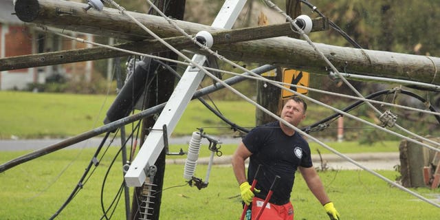 A fireman looks for a place to cut fallen power lines, Friday, Aug. 28, 2020, in Westlake, La., as cleanup efforts continue following Hurricane Laura moved through the area. (Kirk Meche/American Press via AP)