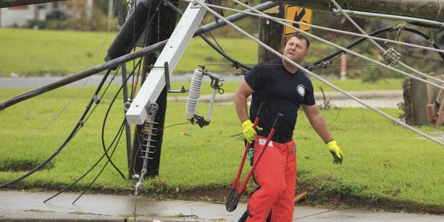 A fireman looks for a place to cut fallen power lines, Friday, Aug. 28, 2020, in Westlake, La., as cleanup efforts continue following Hurricane Laura moved through the area. (Kirk Meche/American Press via AP)