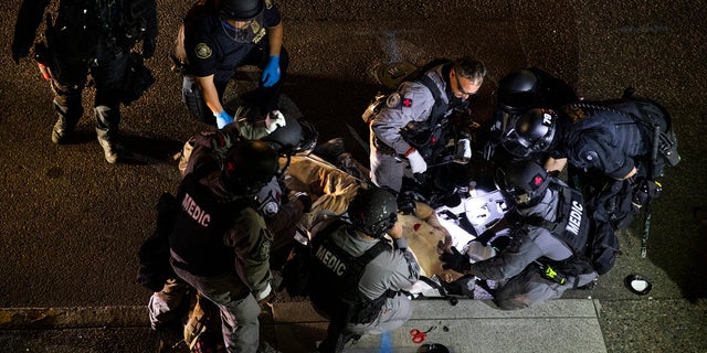 A man is treated after being shot Aug. 29, 2020, in Portland, Ore. It wasn't clear if the fatal shooting was linked to fights that broke out as a caravan of about 600 vehicles was confronted by counterdemonstrators in the city's downtown. (AP Photo/Paula Bronstein)