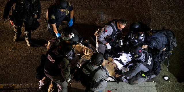 A man is treated after being shot Aug. 29, 2020, in Portland, Ore. It wasn't clear if the fatal shooting was linked to fights that broke out as a caravan of about 600 vehicles was confronted by counterdemonstrators in the city's downtown. (AP Photo/Paula Bronstein)