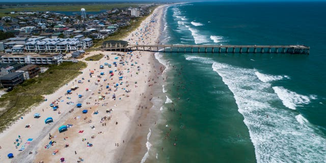 Beachgoers pack Wrightsville Beach, N.C., Sunday, Aug. 2, 2020 as Tropical Storm Isaias moves along the Southeast Coast. (Travis Long/The News & Observer via AP)