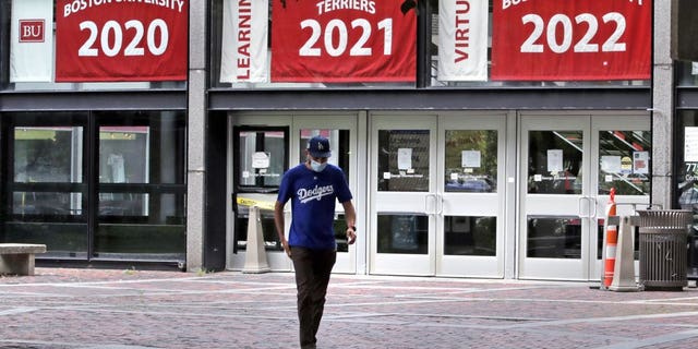 In this July 23, 2020, file photo, Weston Koenn, a graduate student from Los Angeles, leaves the Boston University student union building as he walks through the student-less campus in Boston. As more universities keep classes online this fall, it’s leading to conflict between students who say they deserve tuition discounts and college leaders who insist remote learning is worth the full cost. (AP Photo/Charles Krupa, File)