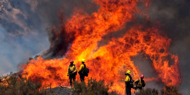 Firefighters watch the Apple Fire in Banning, Calif., Sunday, Aug. 2, 2020.