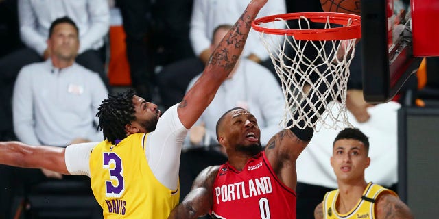 Los Angeles Lakers forward Anthony Davis (3) blocks a shot by Portland Trail Blazers guard Damian Lillard (0) as Lakers forward Kyle Kuzma (0) looks on during the first half of Game 2 of an NBA basketball first-round playoff series, Thursday, Aug. 20, 2020, in Lake Buena Vista, Fla. (Kim Klement/Pool Photo via AP)