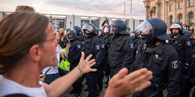 Police officers push away a crowd of demonstrators from the square 'Platz der Republik' in front of the Reichstag building during a demonstration against the Corona measures in Berlin, Germany, Saturday, Aug. 29, 2020. (Christoph Soeder/dpa via AP)
