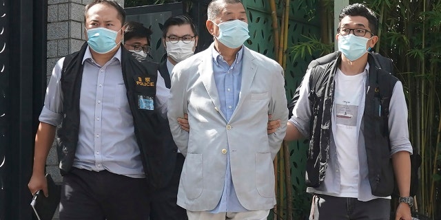 Hong Kong media tycoon Jimmy Lai, center, who founded local newspaper Apple Daily, is arrested by police officers at his home in Hong Kong, Monday, Aug. 10, 2020. (AP Photo)