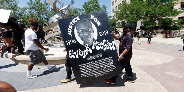 FILE - In this June 27 photo, demonstrators carry a giant placard during a rally and march over the death of 23-year-old Elijah McClain outside the police department in Aurora, Colo. (AP Photo/David Zalubowski, File)