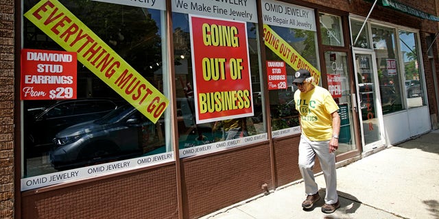 A man walks past a retail store that is going out of business due to the coronavirus pandemic in Winnetka, Ill., Tuesday, June 23, 2020.