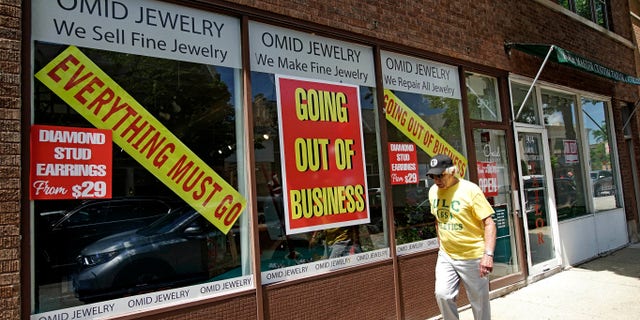 A man walks past a retail store that is going out of business due to the coronavirus pandemic in Winnetka, Ill., Tuesday, June 23, 2020.