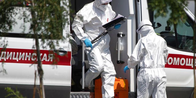 Medical workers wearing protective gear get out from an ambulance as they transport a patient suspected of having coronavirus, at a hospital in Kommunarka, outside Moscow, Russia, Tuesday, July 28, 2020. (AP Photo/Pavel Golovkin)